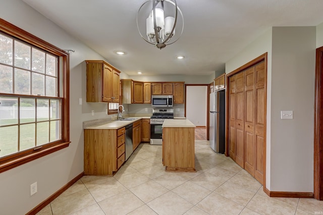 kitchen featuring stainless steel appliances, hanging light fixtures, sink, a chandelier, and a center island