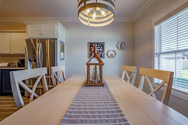 dining room featuring ornamental molding, hardwood / wood-style flooring, a healthy amount of sunlight, and a notable chandelier