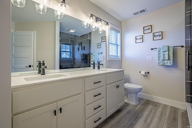 bathroom with toilet, wood-type flooring, vanity, and a shower with door