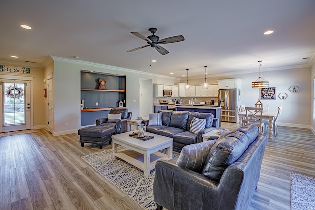 living room with ceiling fan, sink, light hardwood / wood-style floors, and crown molding