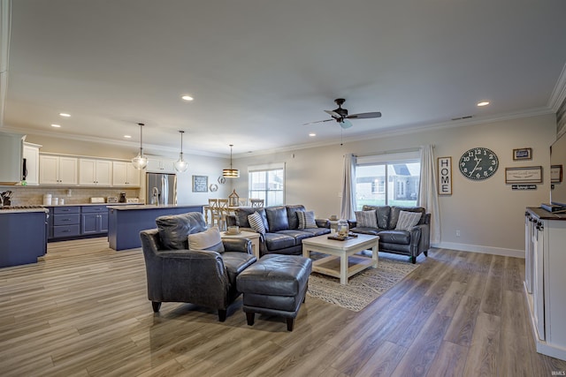 living room featuring light hardwood / wood-style flooring, ceiling fan, and crown molding