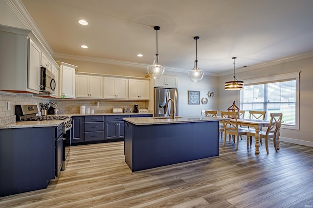 kitchen featuring light hardwood / wood-style floors, white cabinetry, appliances with stainless steel finishes, hanging light fixtures, and a kitchen island with sink