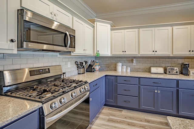 kitchen featuring white cabinets, decorative backsplash, crown molding, and stainless steel appliances