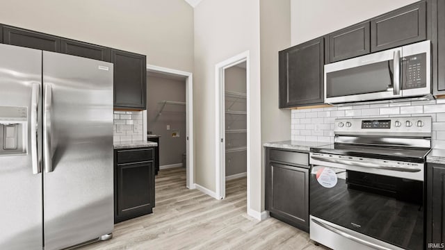 kitchen with light hardwood / wood-style floors, stainless steel appliances, backsplash, and light stone counters