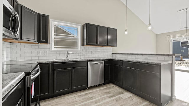 kitchen featuring kitchen peninsula, decorative light fixtures, light hardwood / wood-style floors, appliances with stainless steel finishes, and sink