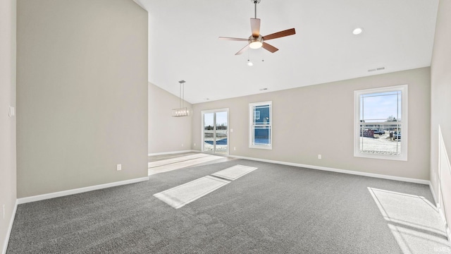 unfurnished living room with ceiling fan with notable chandelier, vaulted ceiling, and carpet