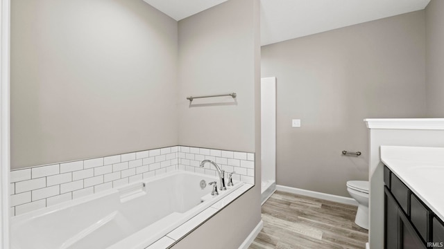 bathroom with hardwood / wood-style flooring, a tub, vanity, and toilet