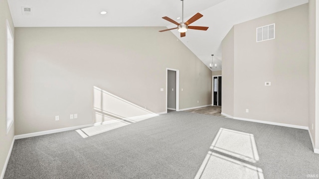 empty room featuring ceiling fan with notable chandelier, high vaulted ceiling, and carpet