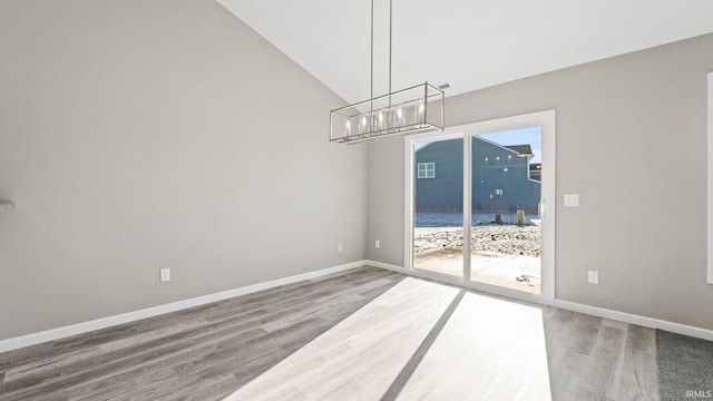 unfurnished dining area featuring lofted ceiling, a healthy amount of sunlight, and wood-type flooring