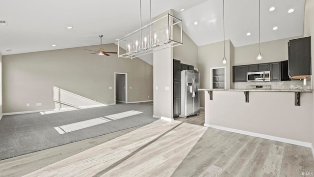 kitchen featuring a breakfast bar area, appliances with stainless steel finishes, kitchen peninsula, ceiling fan, and tasteful backsplash