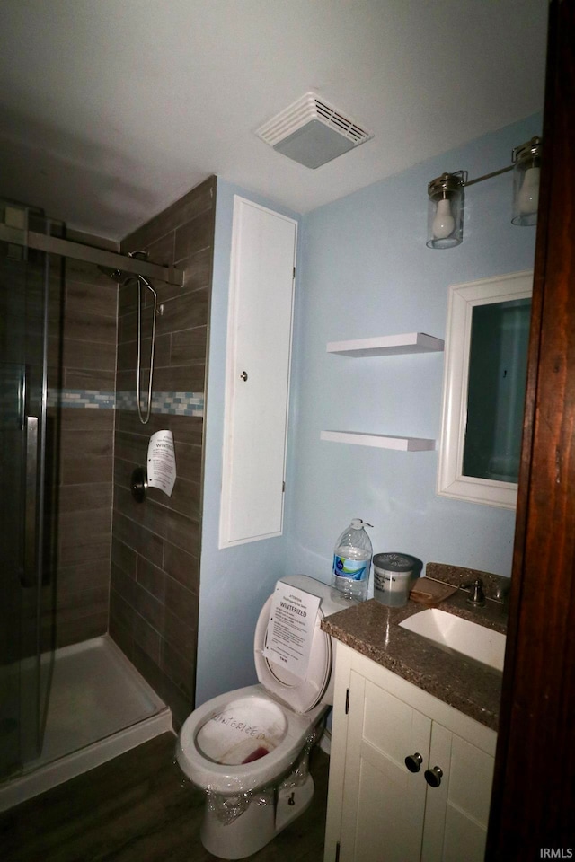 bathroom featuring walk in shower, wood-type flooring, vanity, and toilet