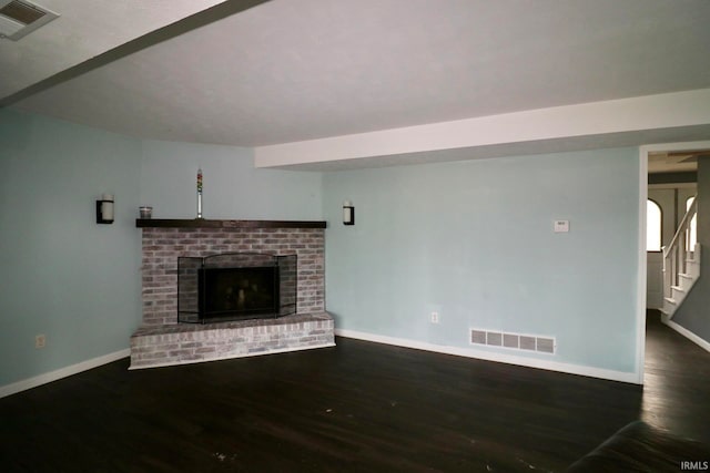 unfurnished living room with dark wood-type flooring and a brick fireplace