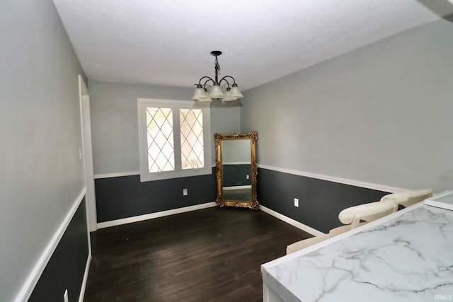 unfurnished bedroom with a textured ceiling, dark hardwood / wood-style floors, and a chandelier