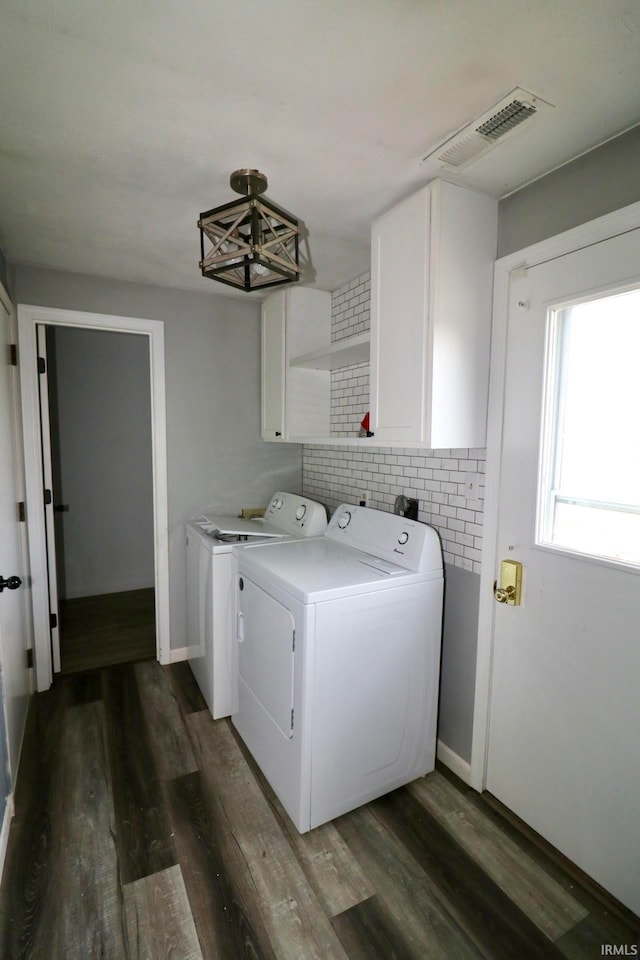 laundry room featuring dark hardwood / wood-style flooring, washing machine and dryer, and cabinets