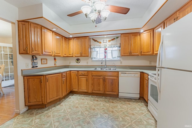 kitchen with white appliances, ceiling fan, sink, and a tray ceiling