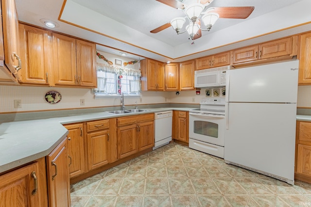 kitchen featuring tasteful backsplash, a raised ceiling, sink, white appliances, and ceiling fan