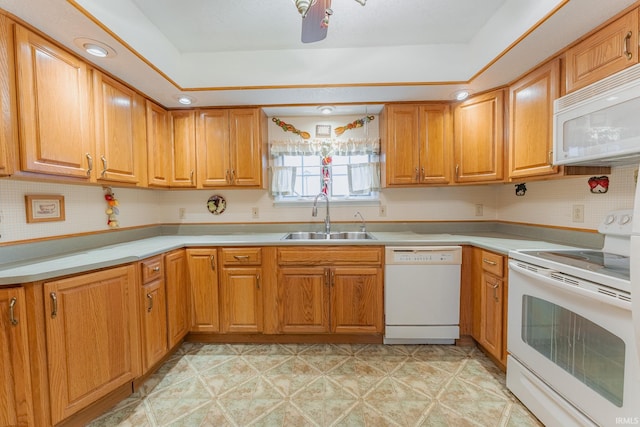 kitchen featuring white appliances, sink, and a tray ceiling