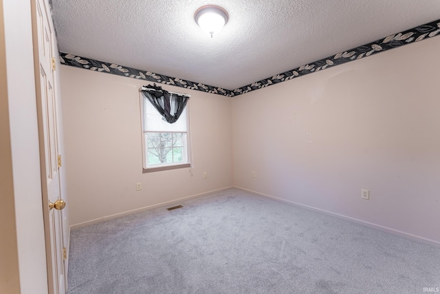 spare room featuring a textured ceiling and light colored carpet