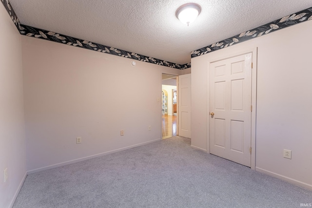 carpeted empty room featuring a textured ceiling