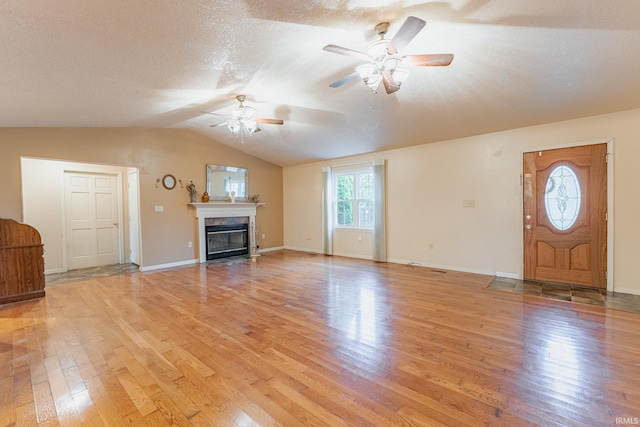 unfurnished living room with a textured ceiling, light wood-type flooring, lofted ceiling, and ceiling fan