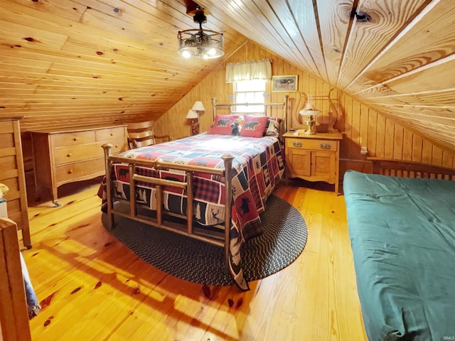 bedroom with light hardwood / wood-style flooring, wood walls, vaulted ceiling, and wooden ceiling