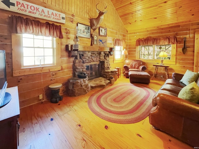 living room with a stone fireplace, wood-type flooring, lofted ceiling, wood ceiling, and wooden walls