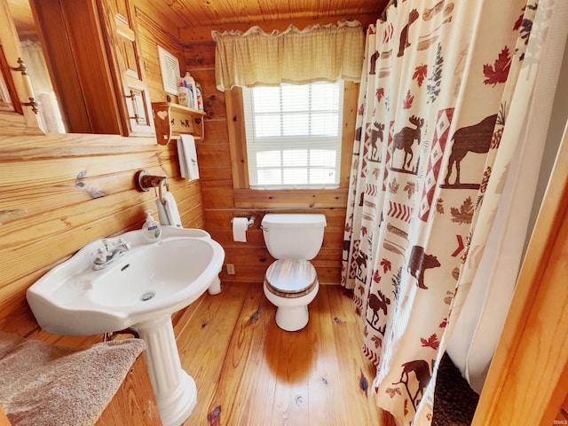 bathroom with toilet, curtained shower, hardwood / wood-style flooring, wooden walls, and wooden ceiling