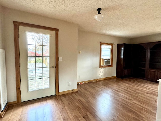 doorway to outside with cooling unit, wood-type flooring, and a textured ceiling