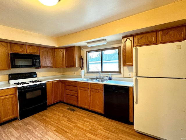 kitchen featuring black appliances, light wood-type flooring, and sink