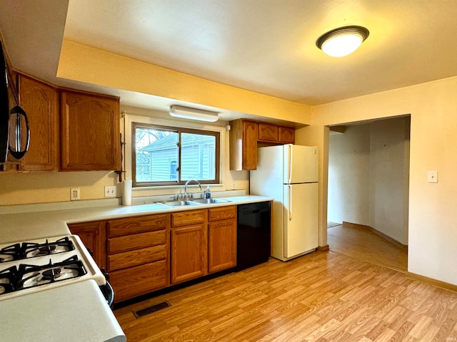 kitchen featuring light wood-type flooring, white appliances, and sink