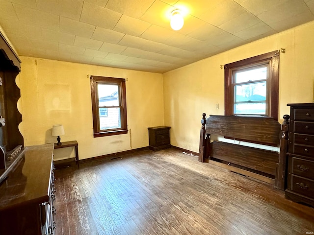 bedroom with dark hardwood / wood-style floors and multiple windows