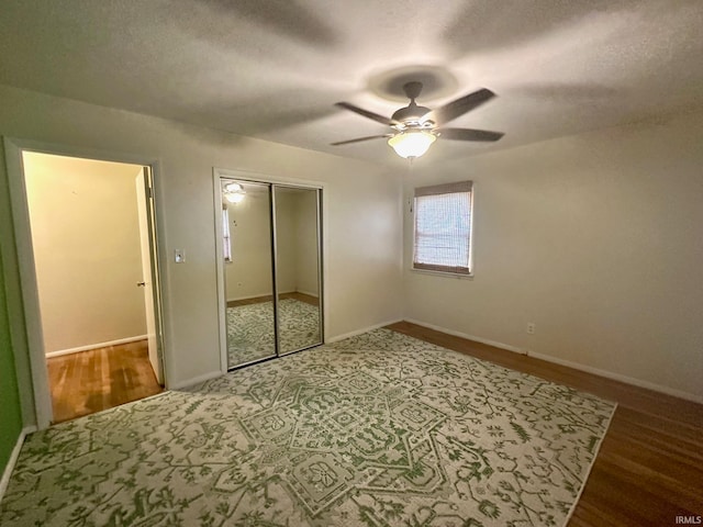 unfurnished bedroom with a textured ceiling, wood-type flooring, ceiling fan, and a closet