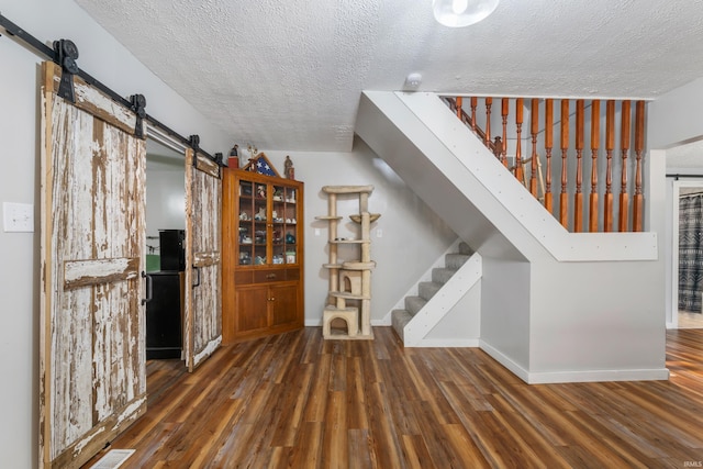 interior space with hardwood / wood-style floors, a barn door, and a textured ceiling