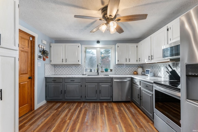 kitchen featuring appliances with stainless steel finishes, dark wood-type flooring, and gray cabinetry