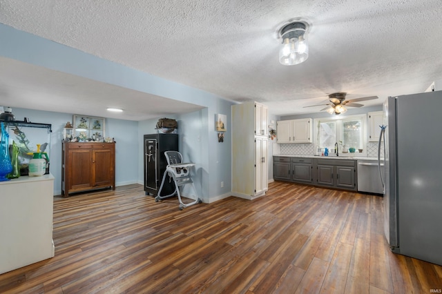 kitchen featuring dark hardwood / wood-style flooring, a textured ceiling, tasteful backsplash, ceiling fan, and appliances with stainless steel finishes