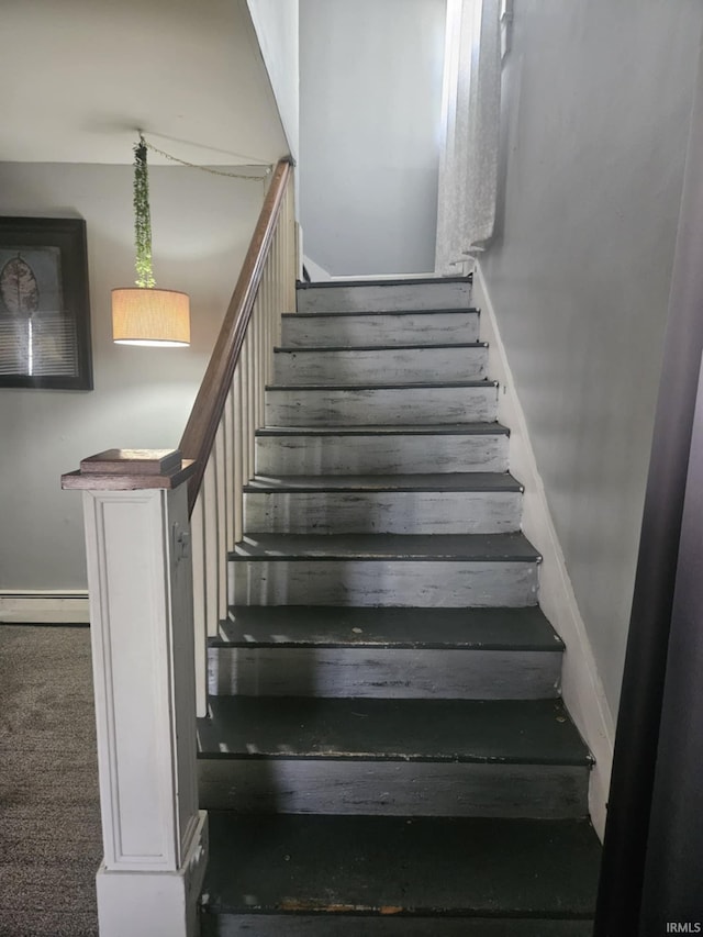 stairway featuring baseboard heating and carpet flooring