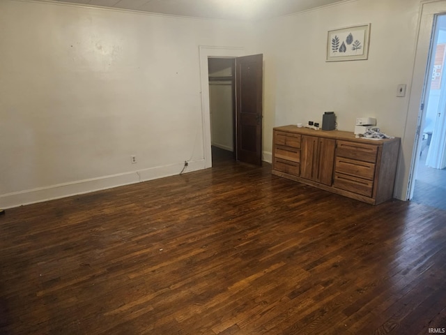 unfurnished bedroom with ornamental molding and dark wood-type flooring