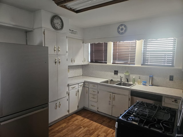 kitchen with hardwood / wood-style flooring, sink, appliances with stainless steel finishes, white cabinets, and decorative backsplash