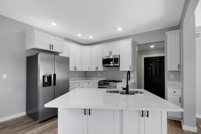 kitchen with white cabinets, hardwood / wood-style floors, appliances with stainless steel finishes, and light stone countertops