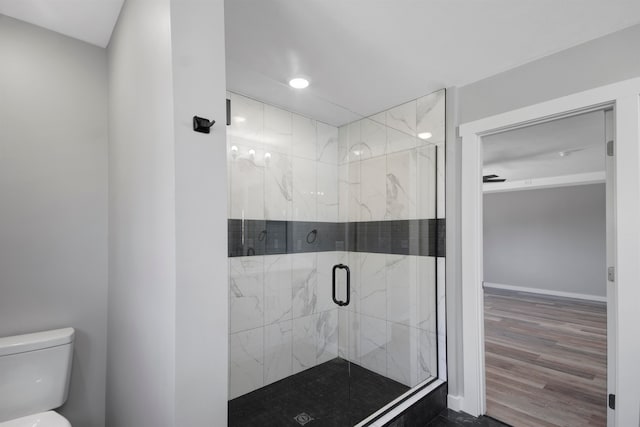 bathroom featuring hardwood / wood-style flooring, toilet, and a shower with shower door