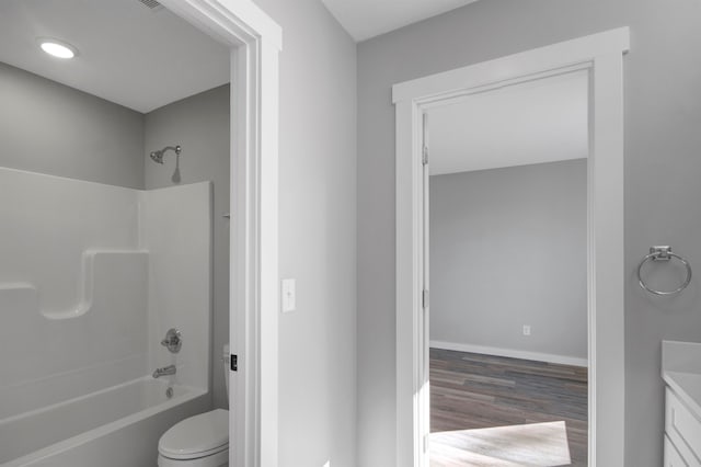 full bathroom featuring hardwood / wood-style floors, vanity, toilet, and  shower combination