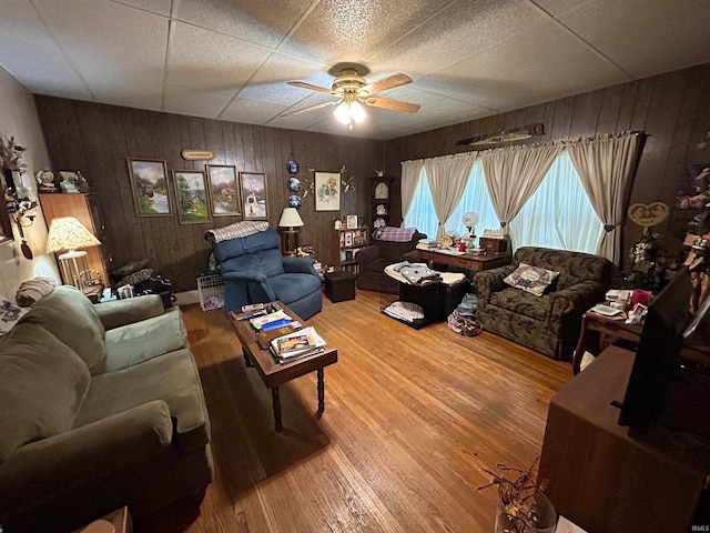 living room featuring hardwood / wood-style floors, wooden walls, and ceiling fan