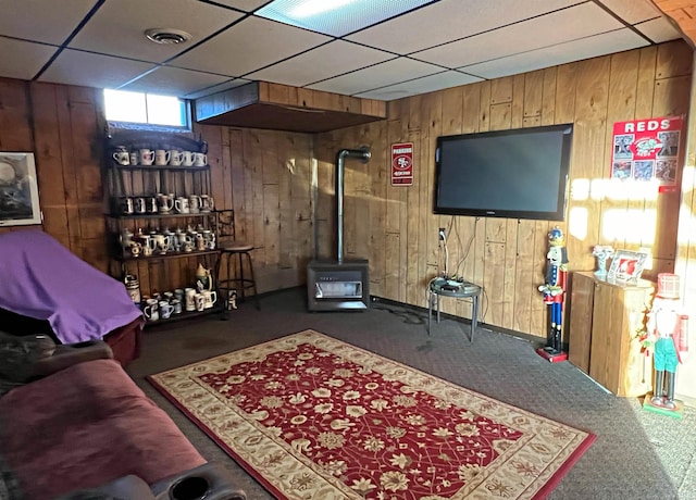 carpeted living room with a drop ceiling and wood walls