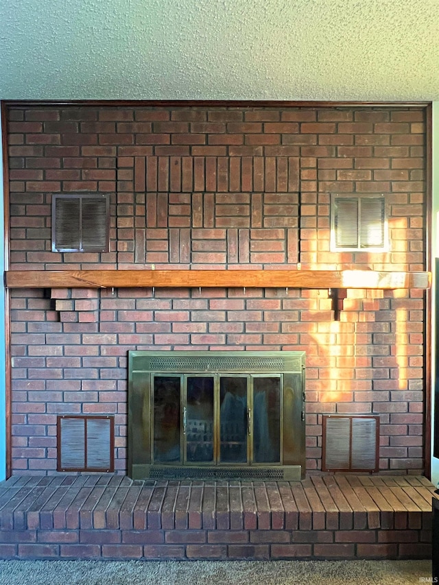 interior details featuring a fireplace, a textured ceiling, and carpet