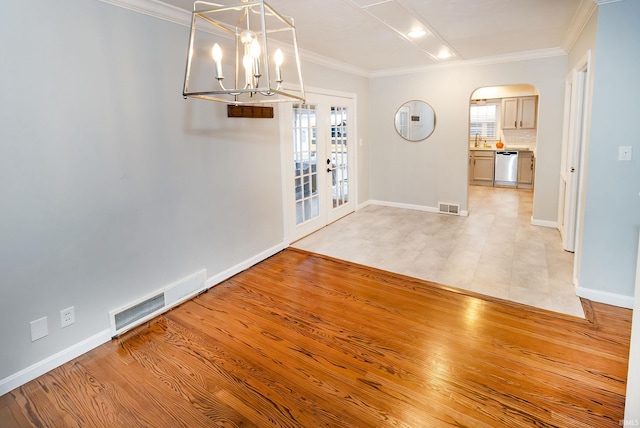 unfurnished dining area featuring french doors, a chandelier, light hardwood / wood-style flooring, and crown molding