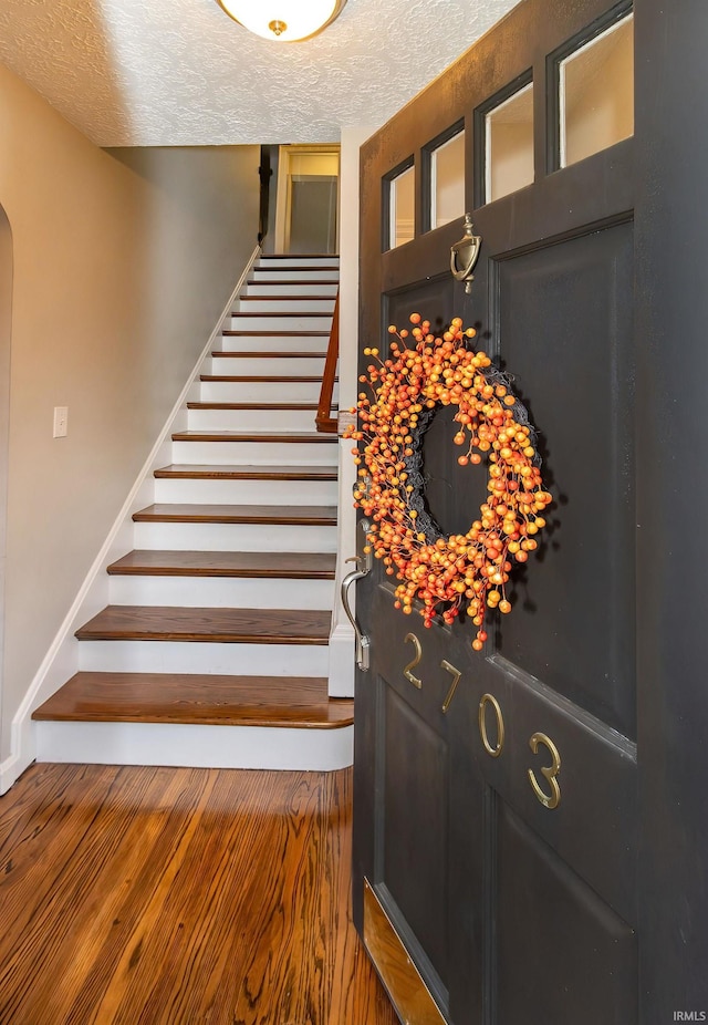 stairway with hardwood / wood-style floors and a textured ceiling