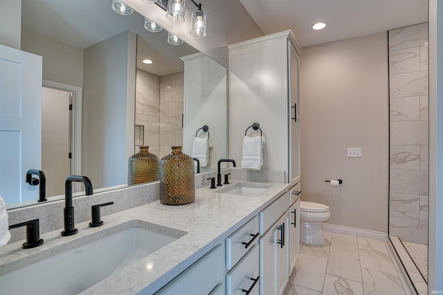 bathroom with a tile shower, vanity, and toilet