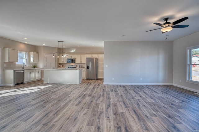 kitchen featuring appliances with stainless steel finishes, decorative light fixtures, a kitchen island, and white cabinets