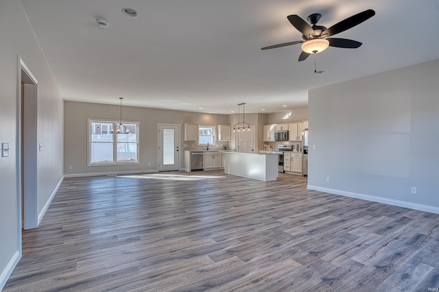 unfurnished living room with ceiling fan with notable chandelier and wood-type flooring