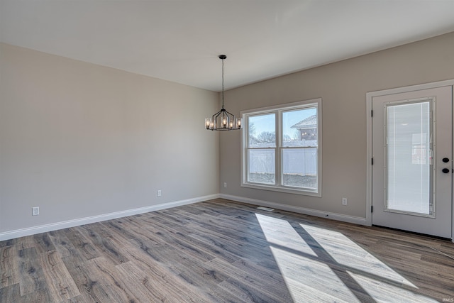 empty room with hardwood / wood-style floors and a notable chandelier